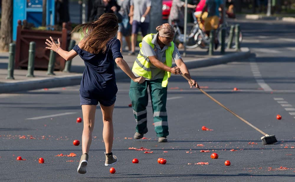 A girl runs to squash tomatoes thrown by activists in front of the government headquarters while attempting to slow down a municipal worker cleaning them up in Bucharest, Romania.