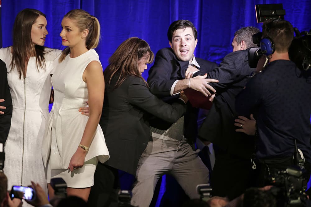 A man is forced off the stage by security as Louise Abbott and Bridget Abbott come to the stage to support their father, Tony, in Sydney following his win in Australia`s national election.