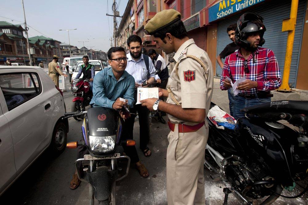A police officer looks at documents of a Kashmiri motorcyclist at a checkpoint during a strike in Srinagar.