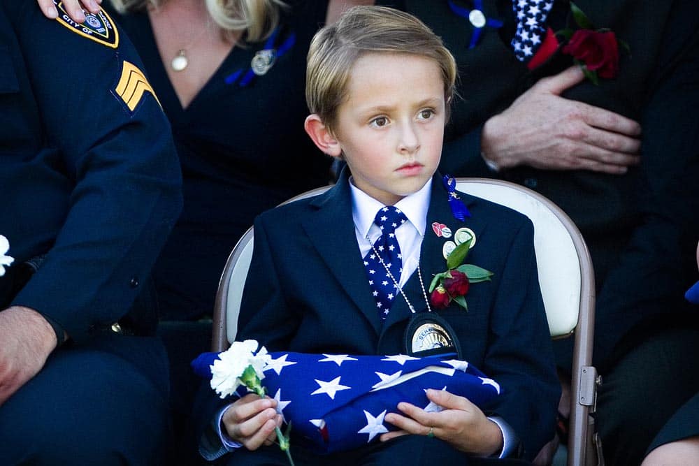Bensen Johnson holds a folded flag during the interment for his father Sgt. Derek Johnson at Larkin Sunset Gardens in Sandy, Utah. Sgt. Johnson, of the Draper Police Department, was killed in the line of duty on Sept. 1.