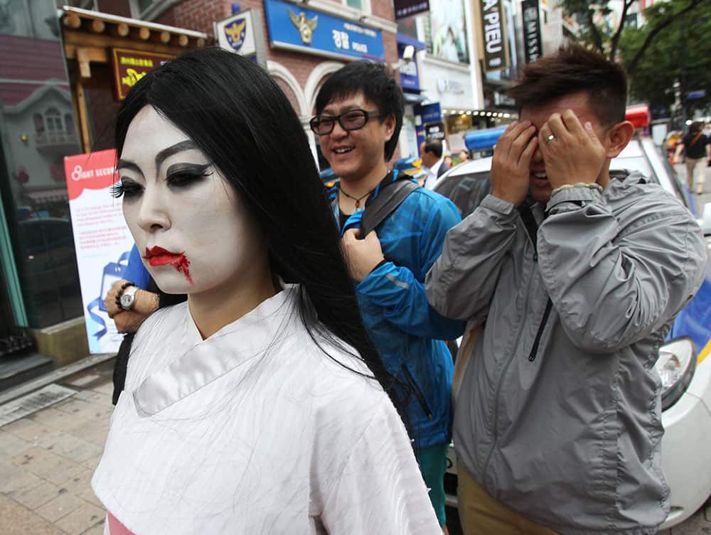 A South Korean employee at the Everland amusement park, wearing a Halloween costume for the upcoming Halloween events, walks on a street as a passer-by covers his eyes in Seoul, South Korea.