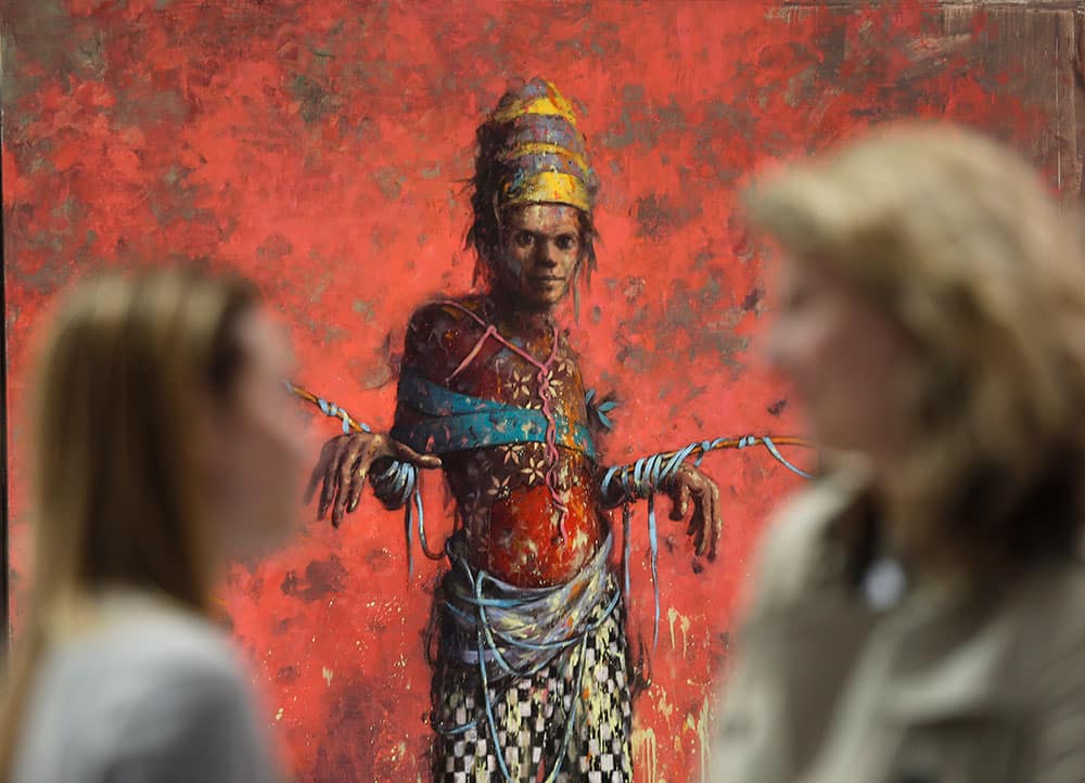 Women talk in front of a painting by Jonas Burgert from the Blain Southern gallery during a private viewing of the ART Rio-International Art Fair in Rio de Janeiro, Brazil.