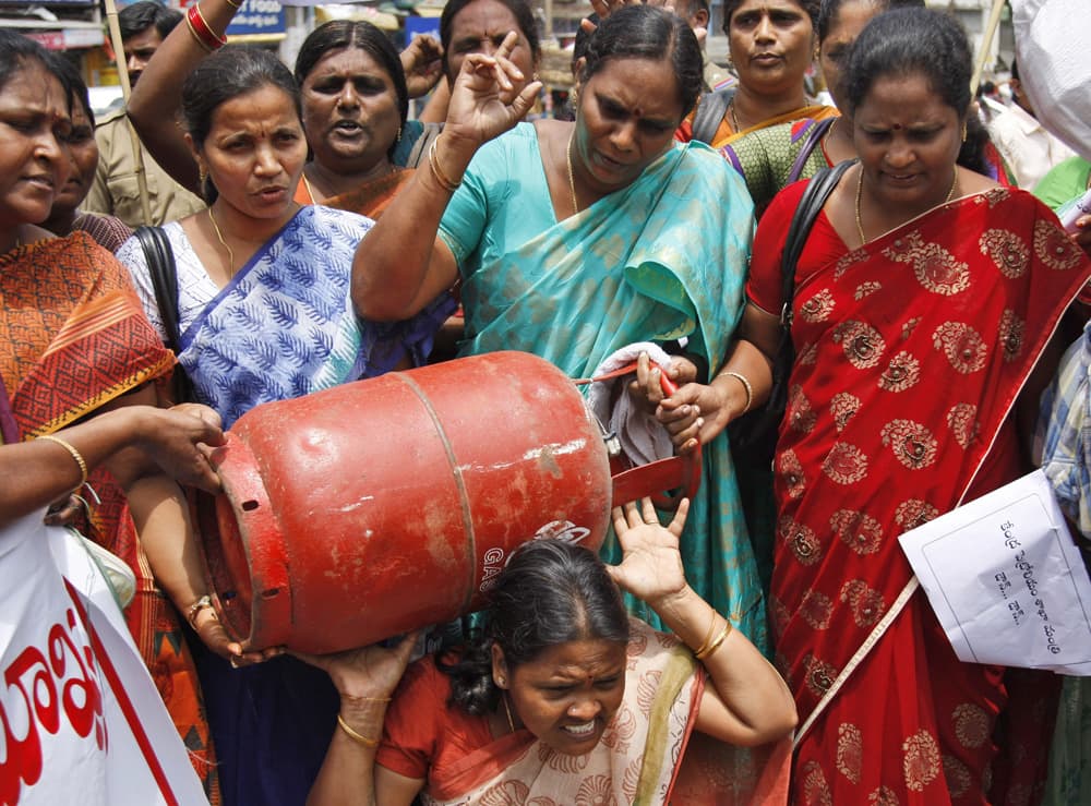 A woman activist carries a liquefied petroleum gas (LPG) cylinder as others shout slogans during a protest in Hyderabad. LPG prices may be raised by Rupees 50 (US$ 0.79) per cylinder, according to news reports.