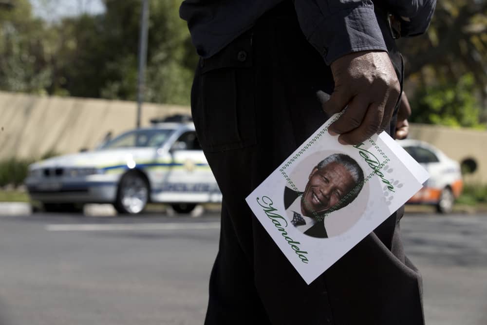 A man carries a get well card for former South African President Nelson Mandela as a group of disabled people from Qwa Qwa, in Free State province, visit the residence where the former president continues to receive medical care, in Johannesburg.
