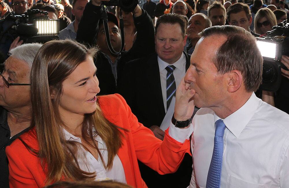 Australia`s opposition leader Tony Abbott, right, has his face wiped clean by his daughter Frances after eating a hot dog during a walk through the Sydney Markets at Flemington in Sydney, Australia.
