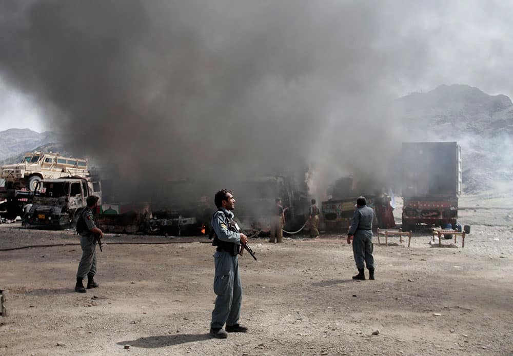 Afghan police officers watch the site of a militant attack at the Torkham area near the Pakistan-Afghanistan border as NATO supply trucks burn in Jalalabad province east of Kabul, Afghanistan.