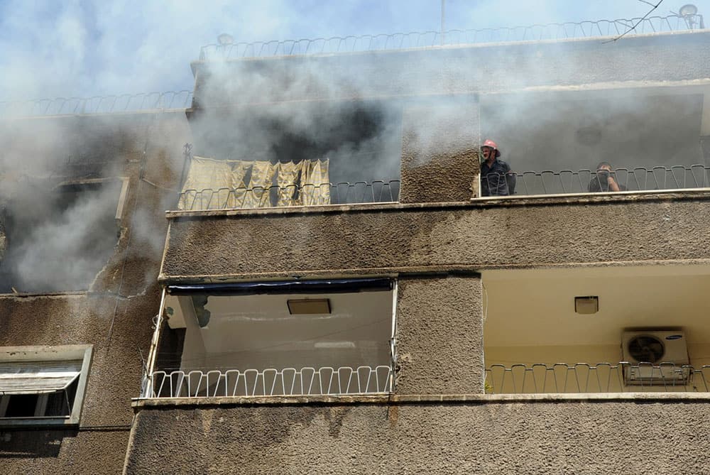 In this photo released by the Syrian official news agency SANA, Syrians firefighters try to extinguish a fire after a missile hit a residential building in Damascus, Syria.