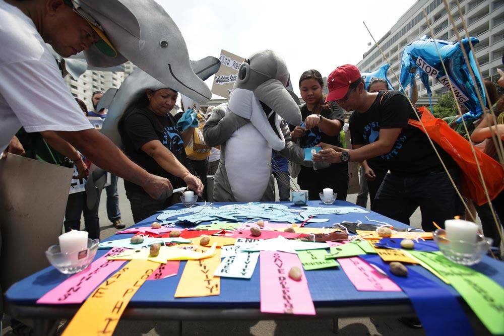Protesters light candles and offer prayers as they perform rituals outside the Japanese Embassy in Pasay, south of Manila, Philippines.