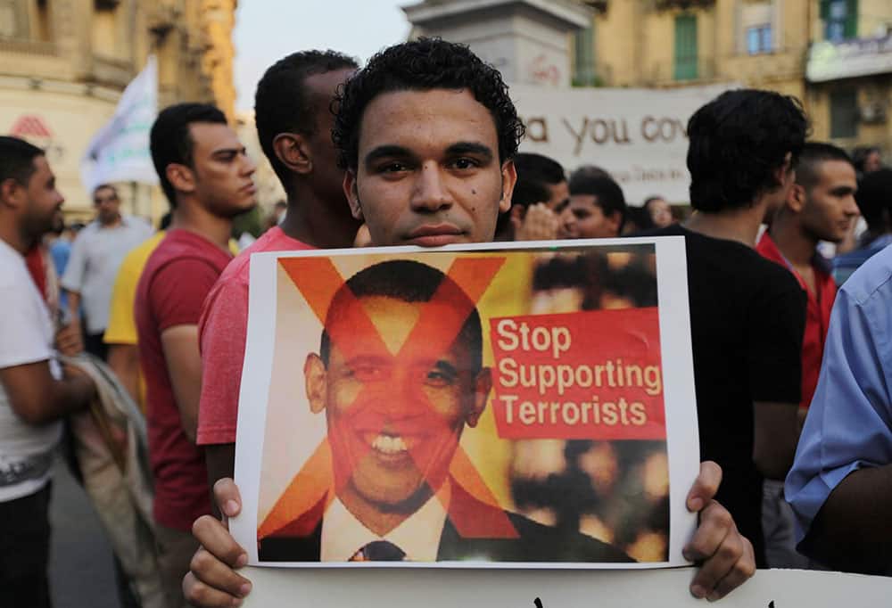 A demonstrator holds a placard with a picture of U.S. President Barack Obama during a protest against possible U.S. forces` strike in Syria, in Cairo, Egypt.