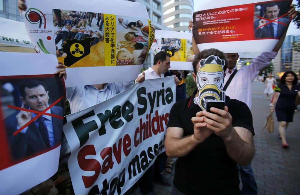 A masked Syrian living in Japan and his supporters display defaced images of Syrian President Bashar Assad during a protest rally in front of the United Nations office in Tokyo.