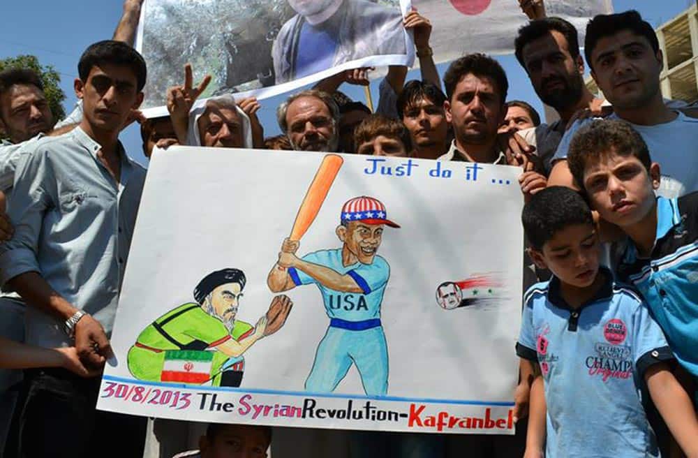 Anti-Syrian regime protesters hold a placard with a sarcastic caricature on it against Hezbollah leader Sheik Hassan Nasrallah, US President Barack Obama and Syrian President Bashar Assad during a demonstration at Kafr Nabil town in Idlib province, northern Syria.