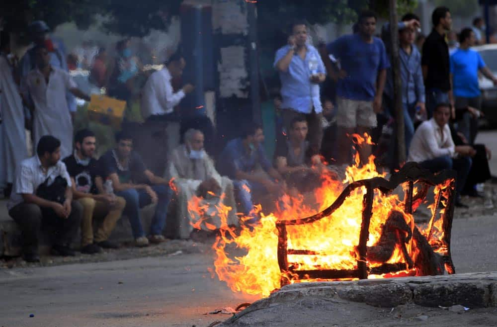 Supporters of Egypt`s ousted President Mohammed Morsi, rest on the roadside behind a burning sofa during a protest in Cairo, Egypt.