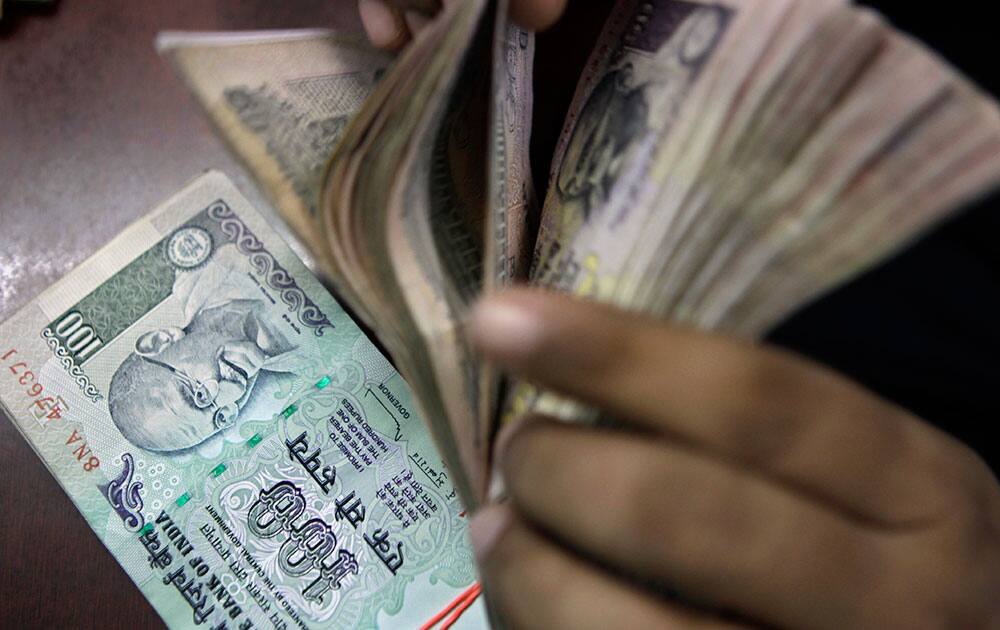 An Indian counts rupee notes at a foreign exchange shop in New Delhi. The rupee rose to 66.85 against the dollar Thursday after a record low of 68.85 per dollar on Wednesday.
