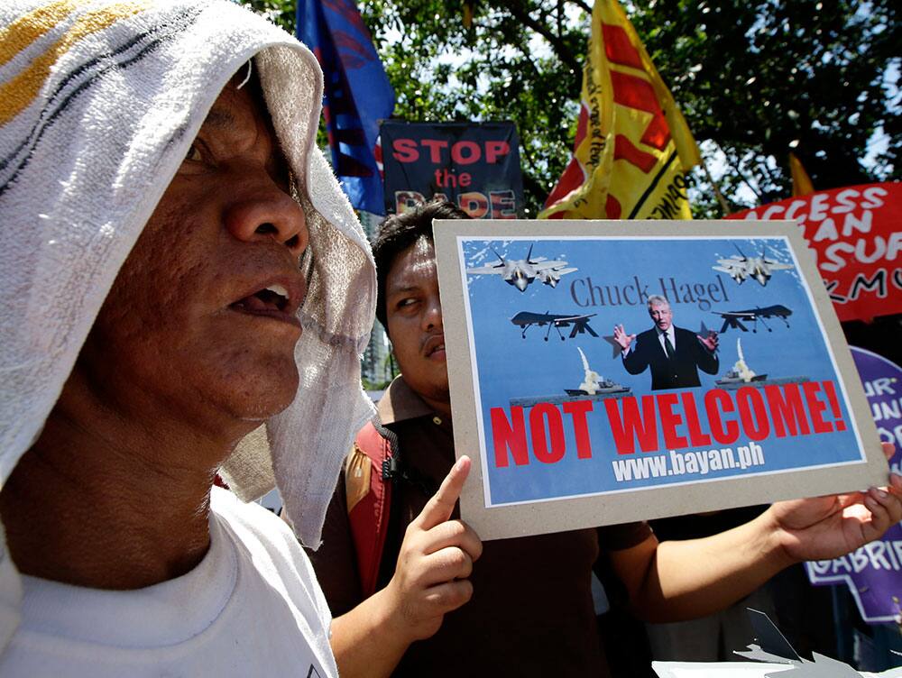 Protesters display placards while shouting slogans during a rally at the US Embassy in Manila, Philippines to protest the two-day visit of US Defense Secretary Chuck Hagel, who arrives later Thursday Aug. 29, 2013.