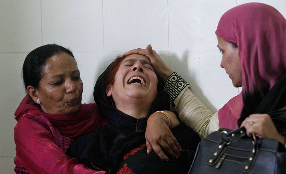 A wailing relative of an injured Kashmiri woman is consoled by others outside a hospital in Srinagar.