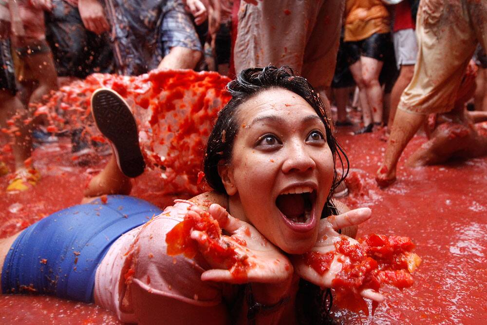 A woman lays on a puddle of tomato juice during the annual