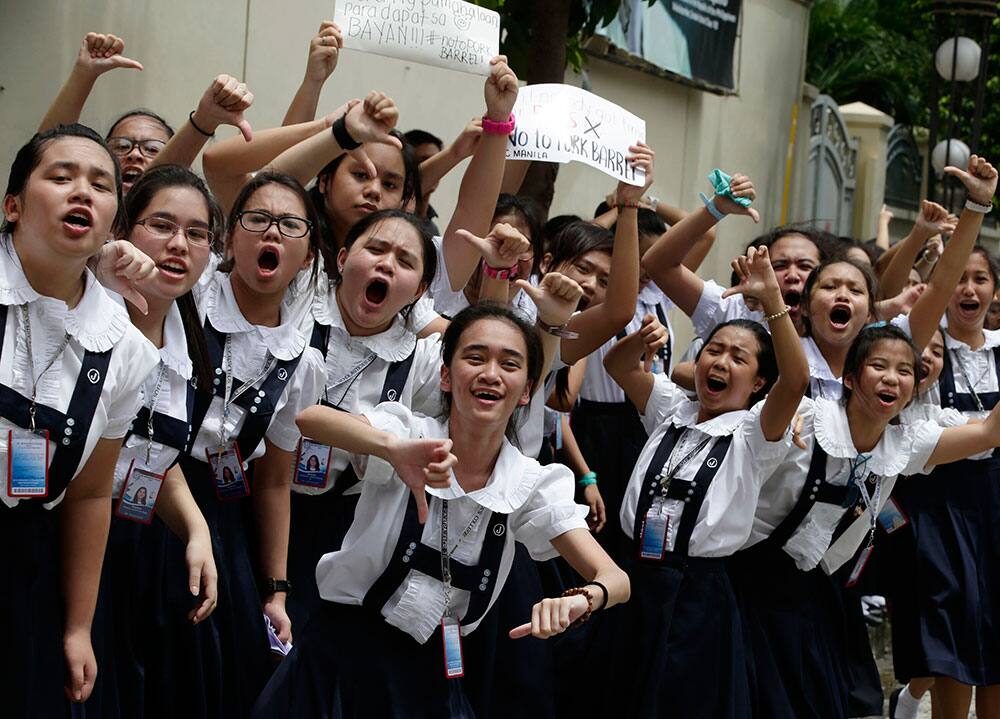 Students of St. Scholastica`s College, a Catholic school, shout slogans and flash thumbs down signs during a