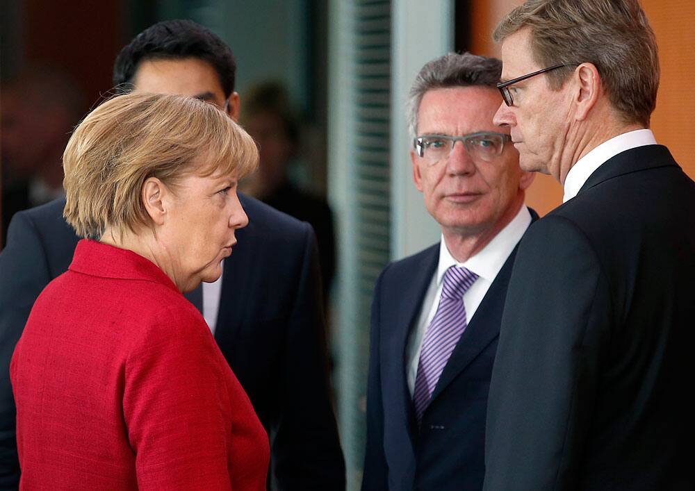 German Chancellor Angela Merkel, left, talks to German Defense Minister Thomas de Maiziere, second right, and German Foreign Minister Guido Westerwelle, right, as she arrives for the weekly cabinet meeting at the chancellery in Berlin, Germany.