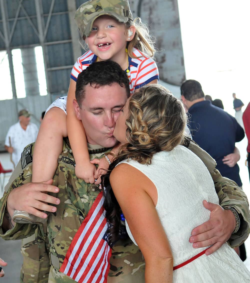 Sgt. Nathan Fitzpatrick gets a kiss from his wife Laura as his daughter Jaycee rides on his shoulders following a homecoming ceremony for the 3rd Combat Aviation Brigade, 3rd Infantry Division at Hunter Army Airfield, in Savannah, Ga.