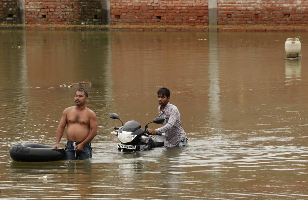 Residents living in low lying area wade through flooded water of the river Ganges following heavy monsoon rains in Allahabad.