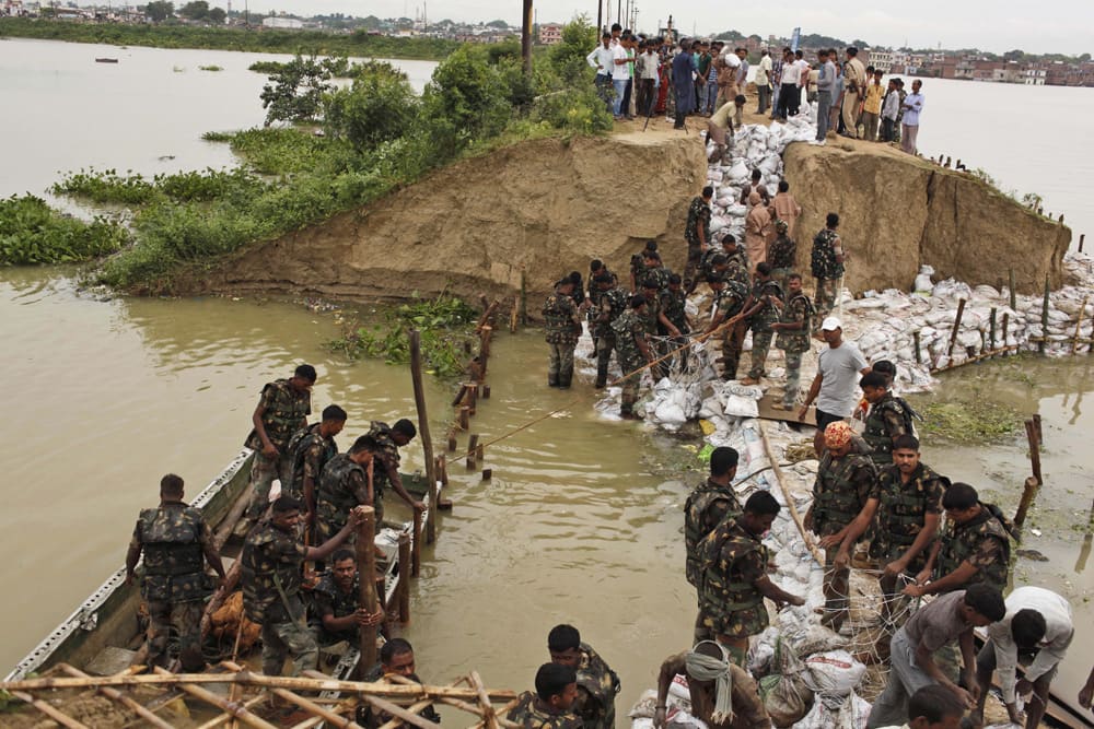 Indian army soldiers repair an embankment which was washed away due to flooding of the river Ganges, in Allahabad.