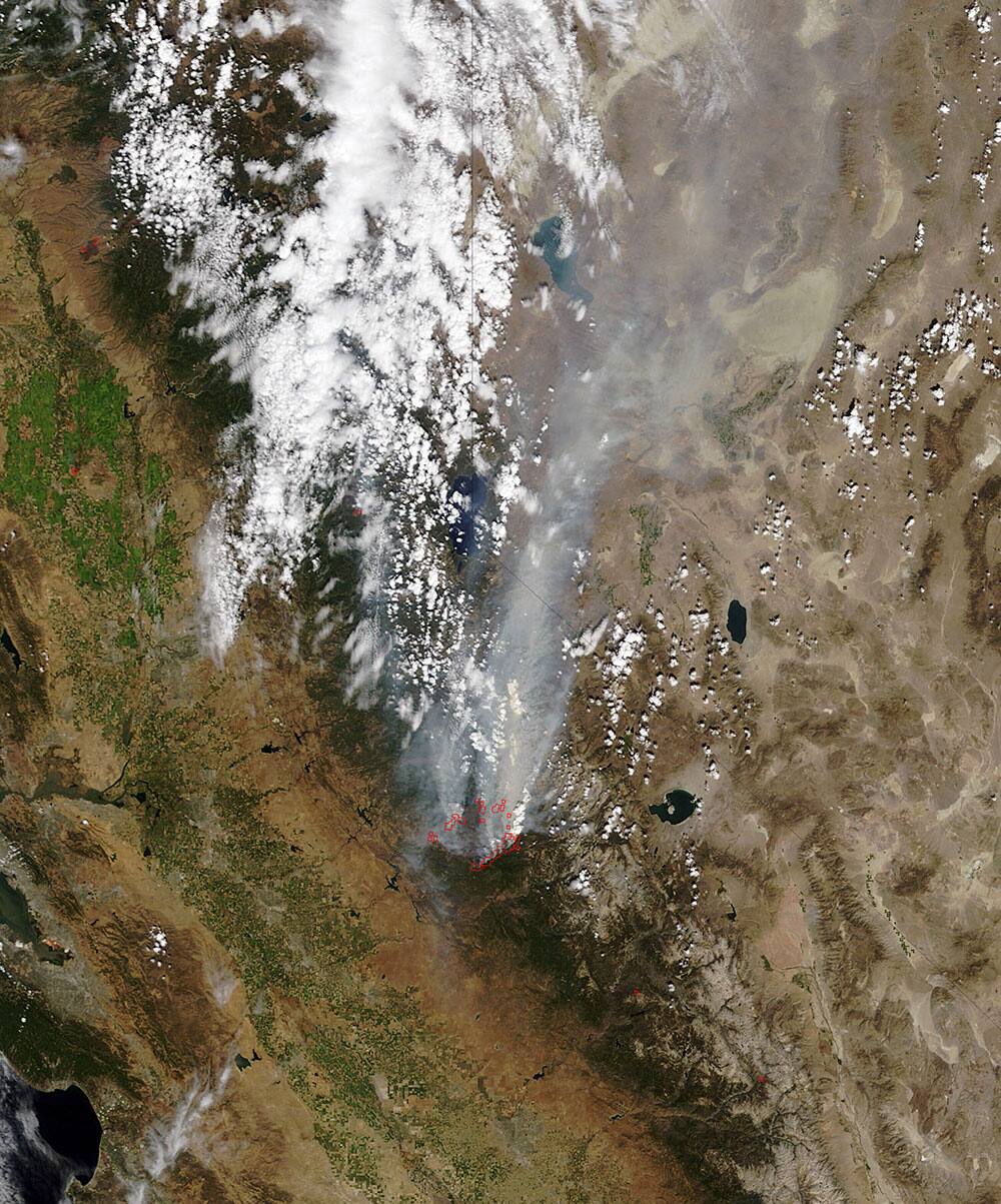 This satellite photo released by NASA, a smoke plume trails north from the drought-fueled Rim Fire, center, burning near Yosemite National Park in central California. Red outlines indicate hot spots where the satellite detected unusually warm surface temperatures associated with fires.