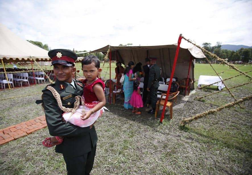 A former Maoist rebel carries his daughter during a ceremony at Nepalese Military Academy in Kharipati, Nepal.