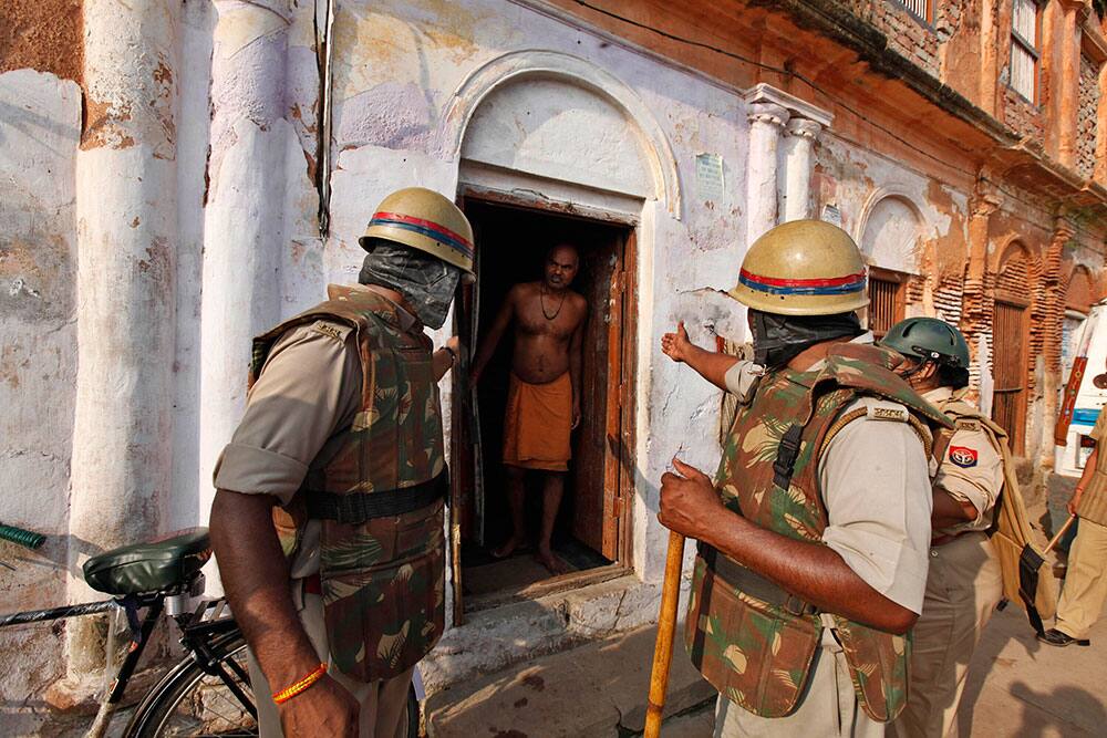 Security personnel deployed near a Hindu temple gesture to a resident to close the door of his house in Ayodhya.