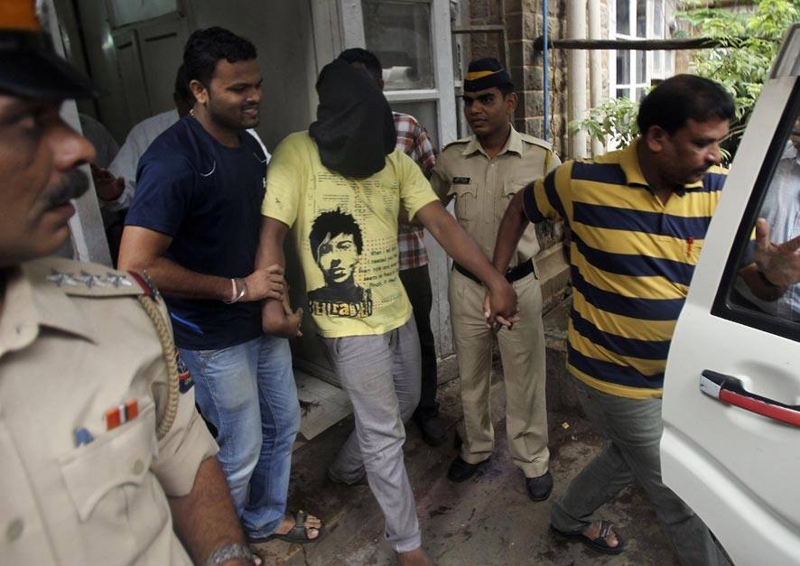 Police officials escort an accused, with the head covered with black cloth, in the gang rape of a photojournalist after producing him before a court in Mumbai.