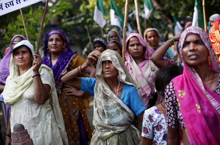 Farmers hold sticks and listen to a speaker during a protest near the Indian Parliament in New Delhi.