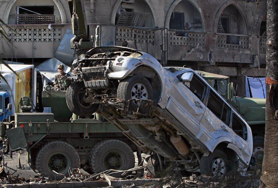 A Lebanese Army soldier moves a damaged car at the site of a car bomb explosion outside of the Al-Taqwa mosque, in the northern city of Tripoli, Lebanon.