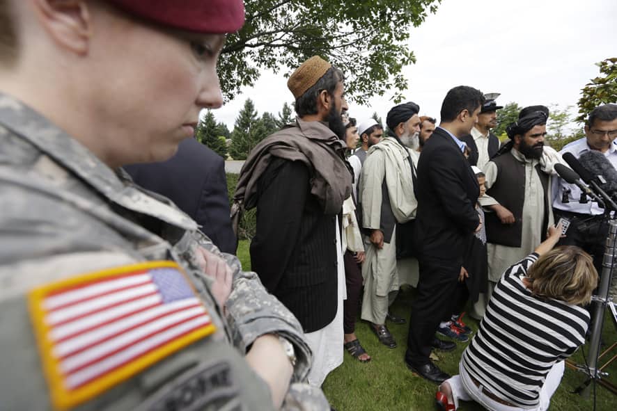 A US soldier looks on as Afghan villagers, some who testified earlier in the week, speak through an interpreter with reporters following a sentencing hearing for Staff Sgt. Robert Bales at Joint Base Lewis-McChord, Wash.