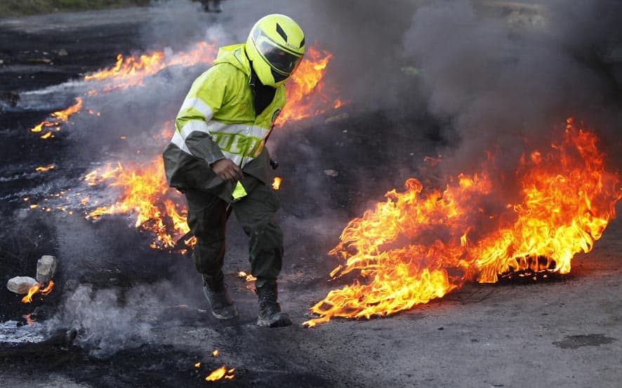 A police officer works to clear a burning barricade set by protesters in Ventaquemada, central Colombia.