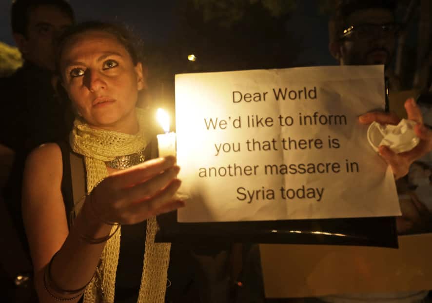 A Syrian woman who lives in Beirut, holds a candle and placard during a vigil against the alleged chemical weapons attack on the suburbs of Damascus, in front of the United Nations headquarters in Beirut, Lebanon.