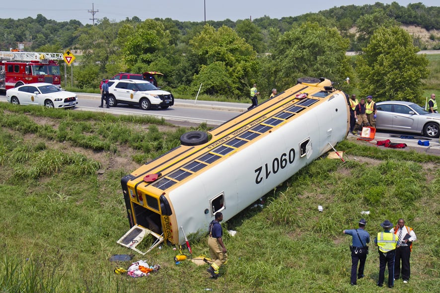 Officials investigate the scene of a school bus accident in Bonner Springs, Kan. One of two buses taking Missouri sixth-graders to an annual campout overturned in northeast Kansas on Wednesday, injuring at least 20 of those onboard, including the driver.