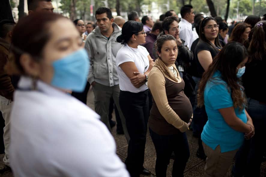 A pregnant woman waits with others outside her office after evacuating due to an earthquake in Mexico City.