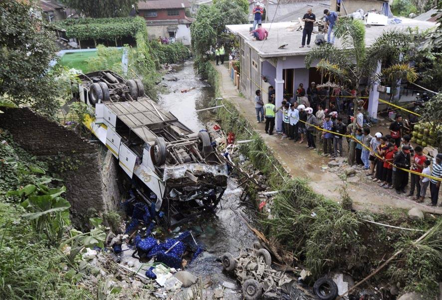Curious onlookers inspect the wreckage of a bus that plunged into a stream in Cisarua, West Java, Indonesia.