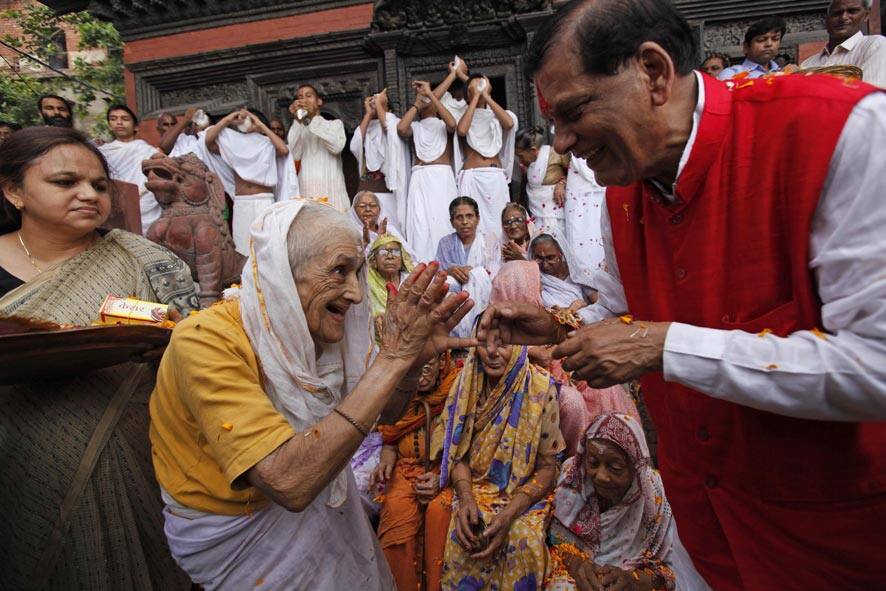 An Indian widow, second left, gestures after tying a