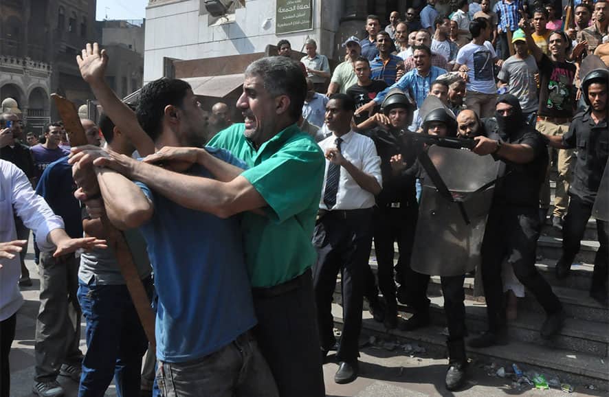 Egyptians security forces escort an Islamist supporter of the Muslim Brotherhood out of the al-Fatah mosque and through angry crowds, after hundreds of Islamist protesters barricaded themselves inside the mosque overnight, following a day of fierce street battles that left scores of people dead, near Ramses Square in downtown Cairo, Egypt.