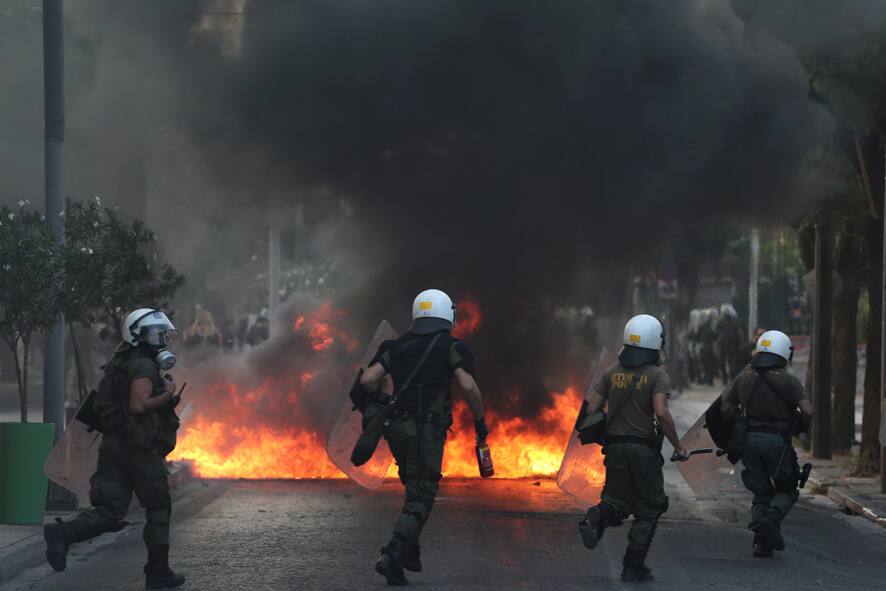 Riot police run towards a fire barricade at the Athens`s suburb of Peristeri. Technical school student Thanassis Kanaoutis, 19, fell to his death Tuesday night when the trolley bus doors unexpectedly opened following an altercation with an inspector because he hadn`t validated his ticket.