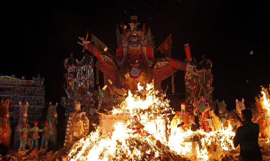 A man sets fire to a giant paper-made statue of Chinese deity know as
