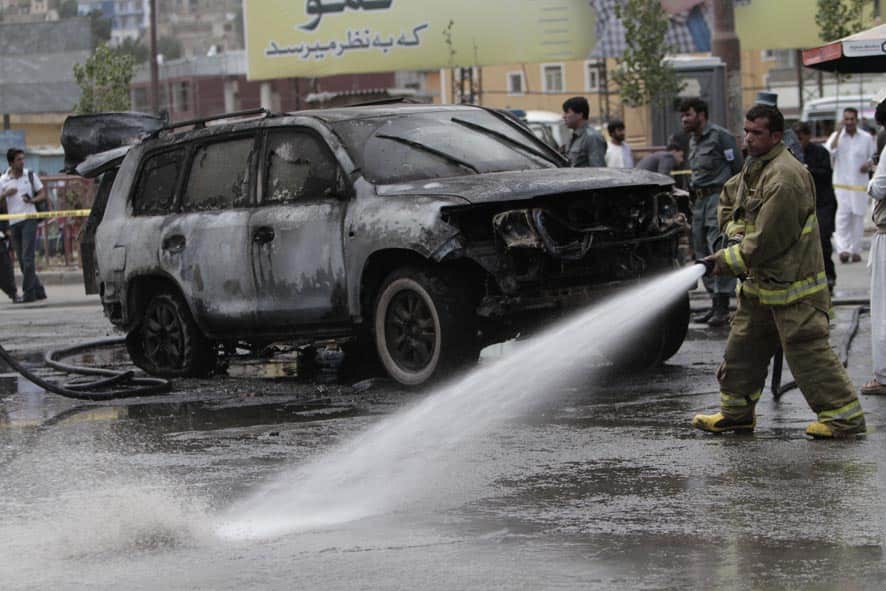 Afghan security forces investigate the scene of an explosion while firefighters spray water on the area, in Kabul, Afghanistan.