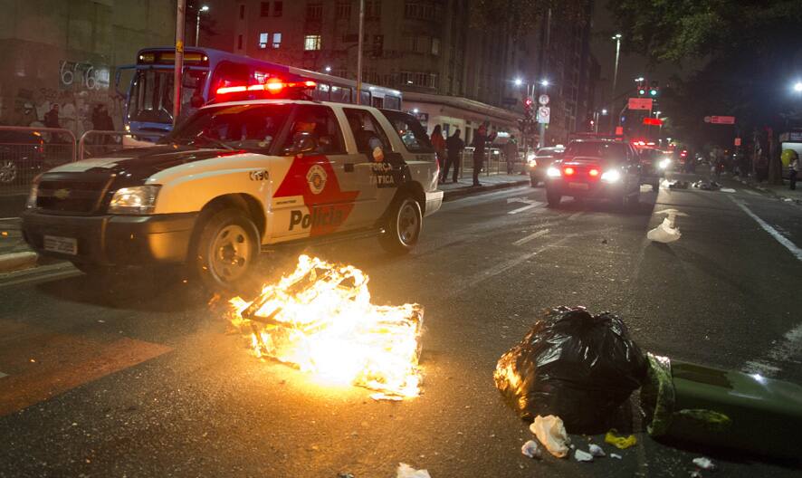 A police vehicle drives past a burning trash during a protest against Sao Paulo Governor Geraldo Alckmin in Sao Paulo, Brazil.