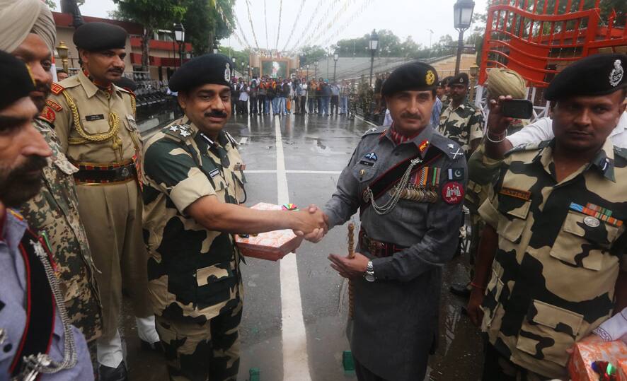 Pakistan troops, right, give sweet to their Indian counterparts on the occasion of Pakistan`s Independence Day at Wagah border in Pakistan.