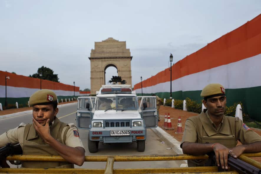 Indian policemen guard the India Gate monument, draped with colors of the Indian flag on the eve of Independence Day in New Delhi.