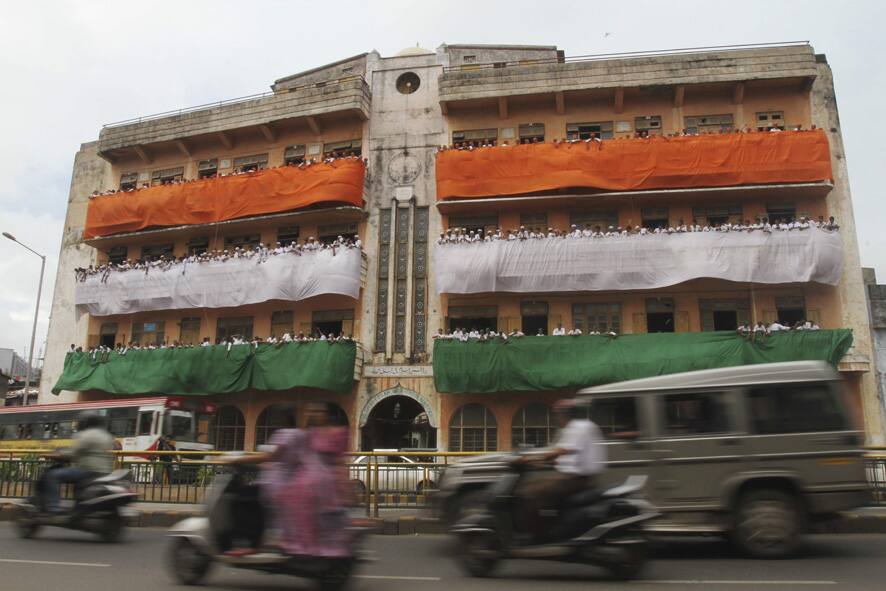Commuters ride past a school building where colors of the Indian flag are displayed on the eve of Independence Day in Ahmadabad.