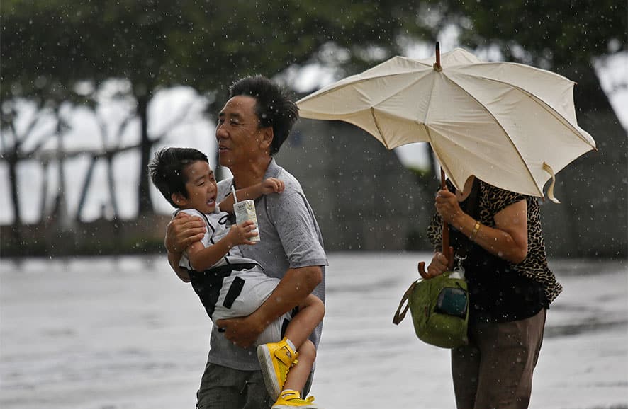 A family from Mainland China battle against strong wind near the waterfront in Hong Kong. Typhoon Utor lashed Hong Kong with wind and rain, closing down the bustling Asian financial center Wednesday before sweeping toward mainland China.