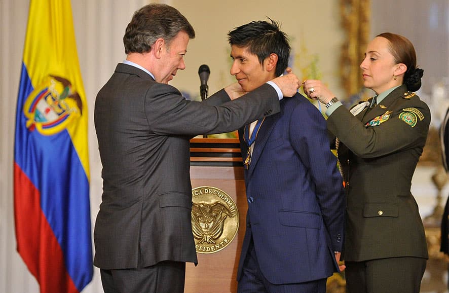 Colombia cycling rider Nairo Quintana, center, is decorated with the Grand Cross of the Order of Boyaca by Colombia`s President Juan Manuel Santos at the Presidential Palace in Bogota, Colombia.