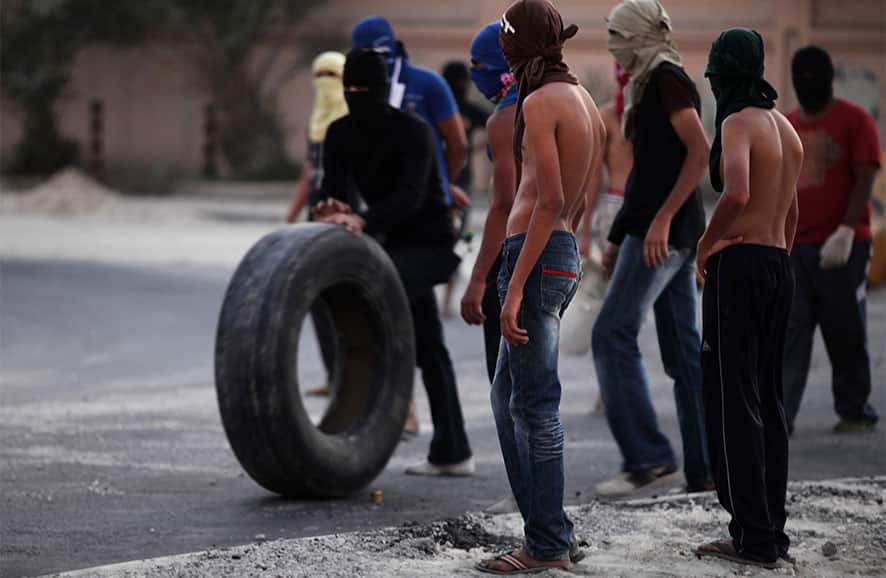 A Bahraini anti-government protester rolls a tire towards burning tires on a street in the western village of Malkiya, Bahrain.