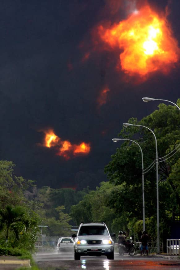 People look at smoke from a refinery fire in Puerto La Cruz, Venezuela. Lightning set fire to a storage tank at Venezuela`s Puerto La Cruz oil refinery and residents were moved out of the immediate area while local media showed images of thick black smoke rising from the facility.